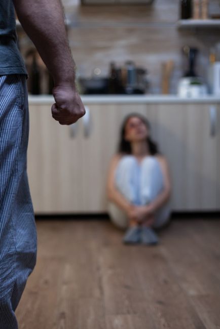 Woman sitting on floor crying and a man making a fist